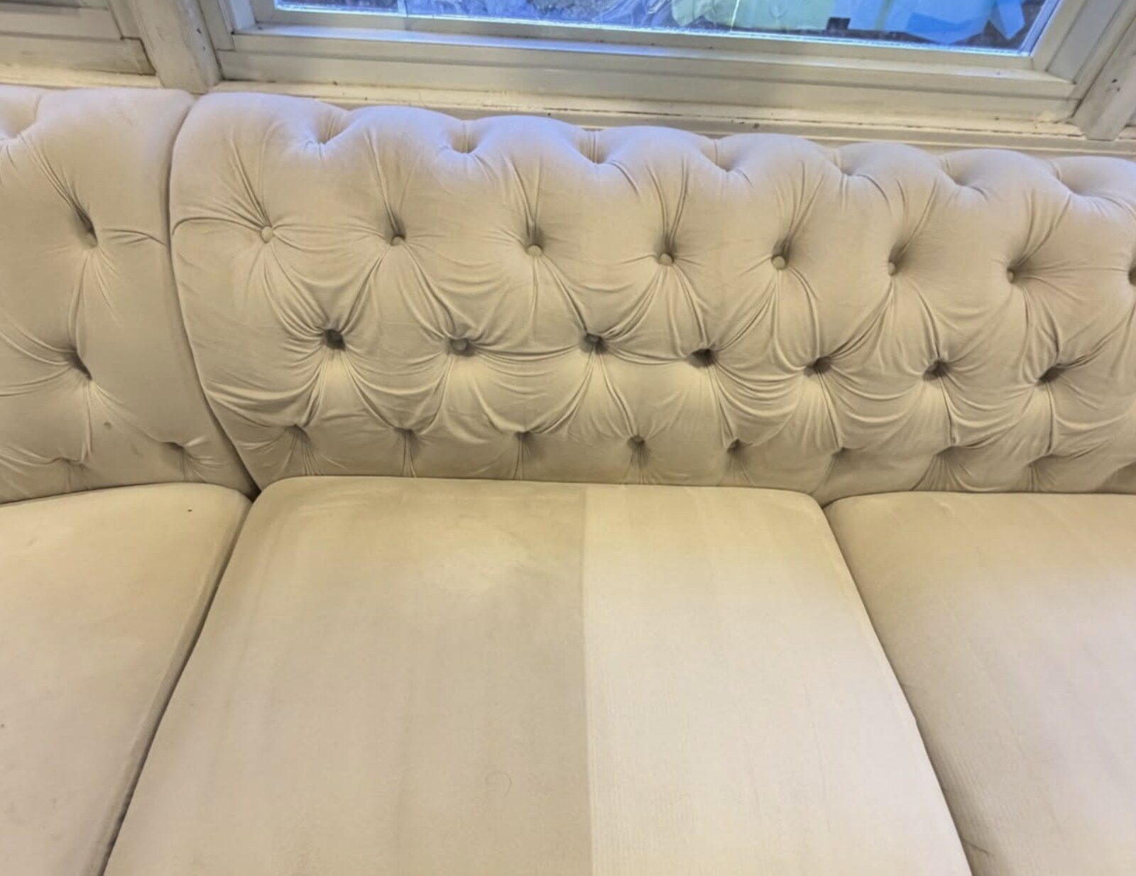 Half-cleaned white sofa showing the difference after professional upholstery cleaning